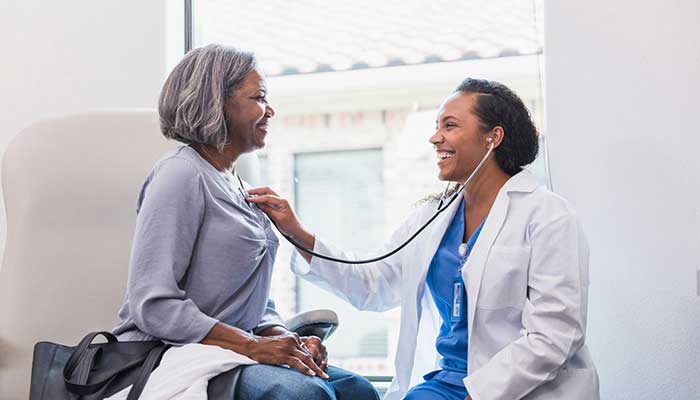 An elderly patient has her heart checked by a doctor