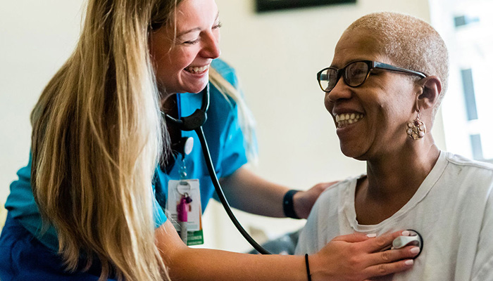 A female nurse listening to an older patient's heart with a stethoscope